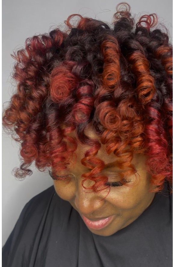 Guest with tightly defined spiral curls in burgundy and copper tones
