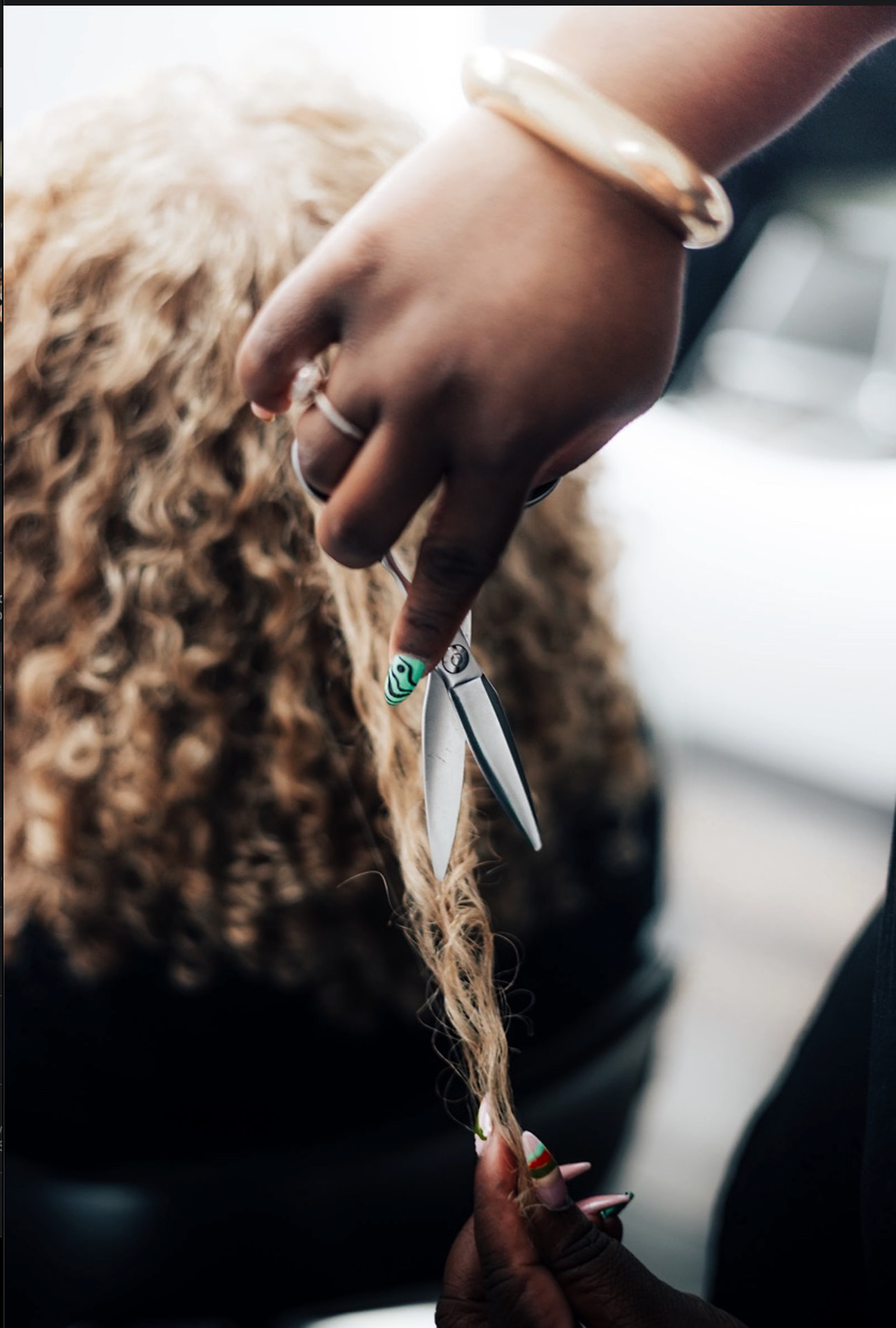 Stylist's hands cutting defined natural curls with shears